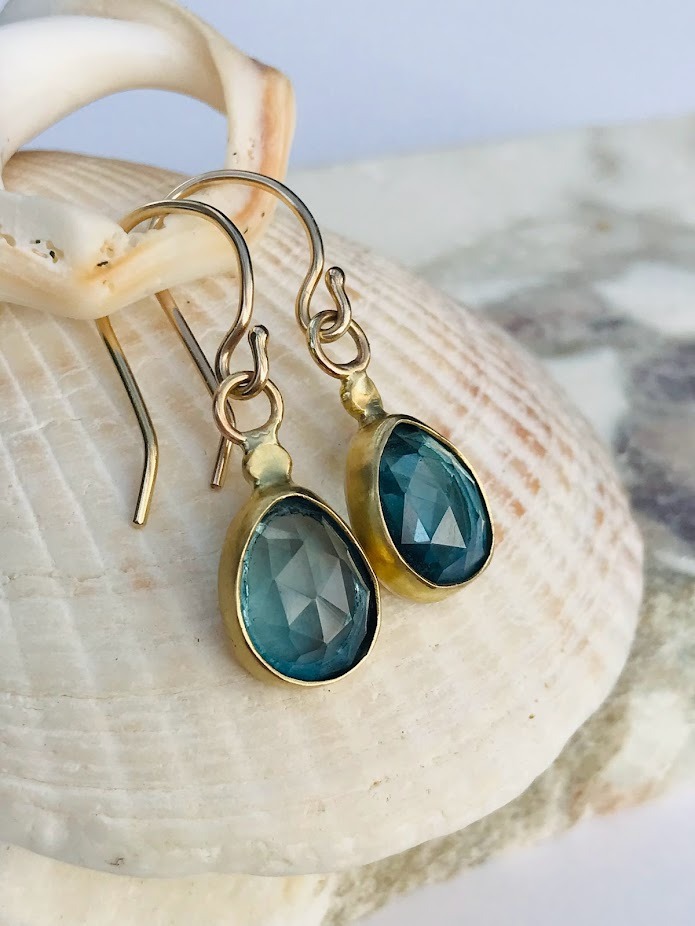 Gold Blue Topaz earrings set on a shell