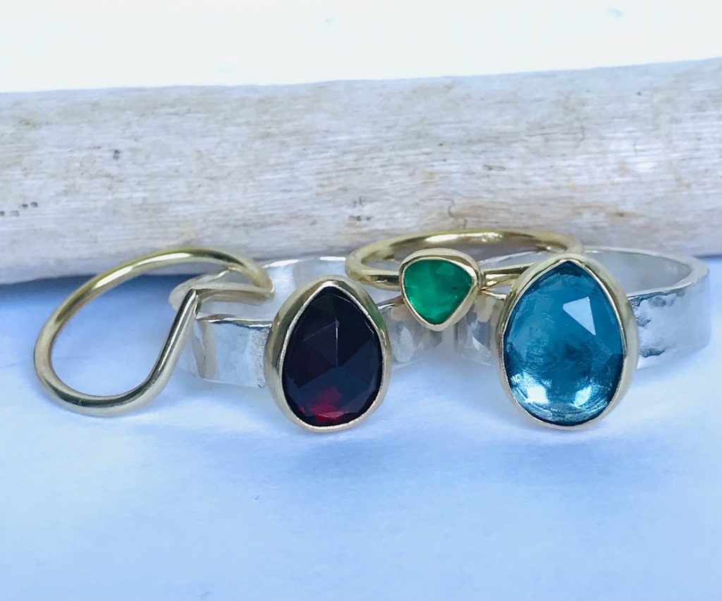 Green Emerald, Blue Topaz, and Red Garnet rings with silver and gold bands